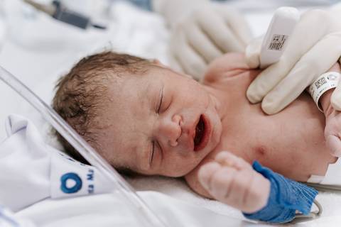 Foto do recém-nascido recebendo cuidados da equipe médica'