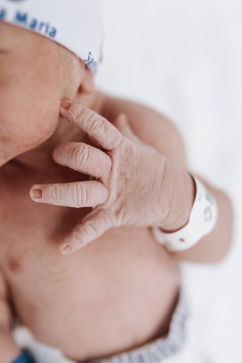 Foto do detalhe da mão do recém-nascido com pulseira hospitalar'