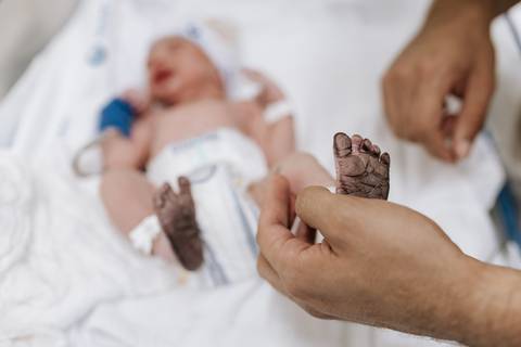 Foto do pai segurando o pé do recém-nascido'