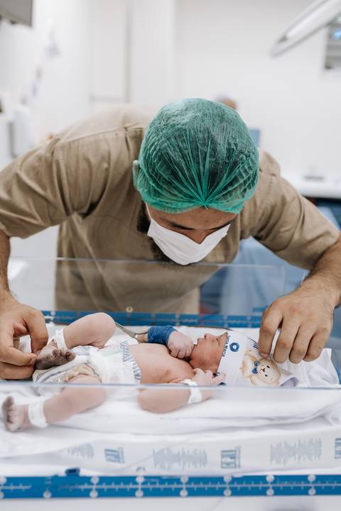 Foto do pai observando o recém-nascido no berçário'