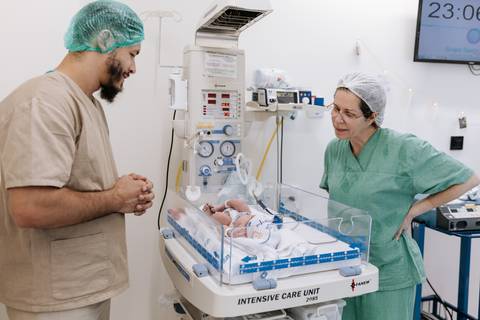 Foto da equipe médica com o bebê e pai'