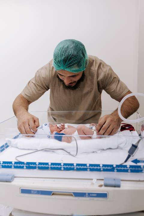 Foto do pai observando o recém-nascido no berço aquecido'