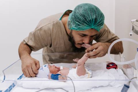 Foto do pai beijando o pé do bebê na maternidade'