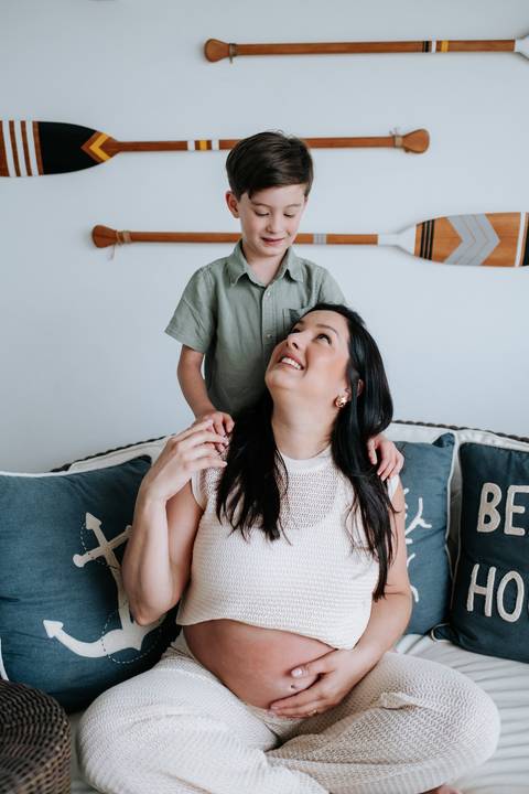 Foto do filho abraçando a mãe grávida.'