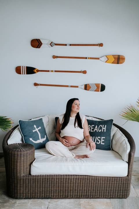 Foto da gestante sentada no sofá em ensaio interno'