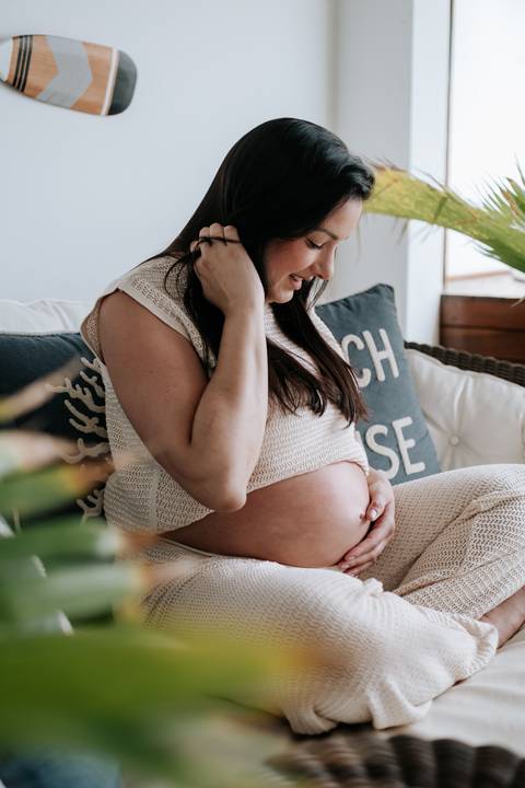 Foto aproximada da barriga de grávida com as mãos da gestante'