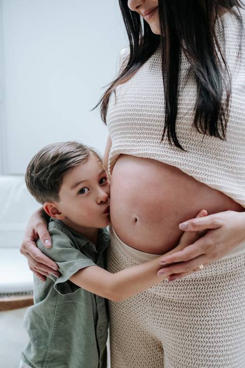 Foto do filho beijando a barriga da mãe gestante'