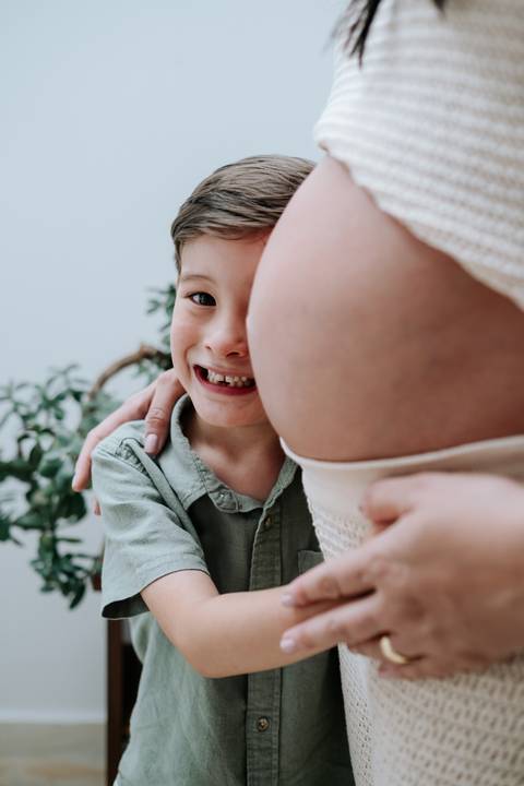 Foto do rosto do filho sorrindo ao lado da barriga da mãe'