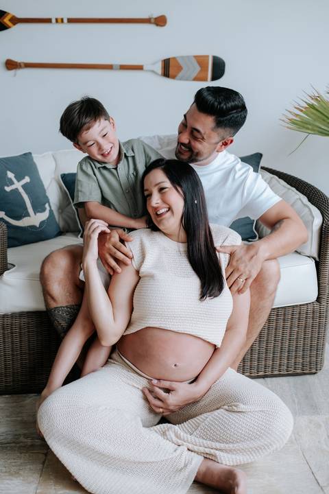 Foto do casal com o filho no sofá durante ensaio gestante'