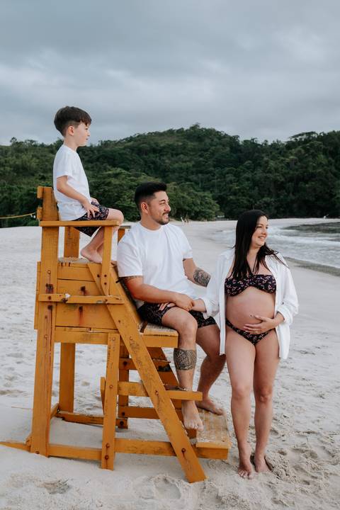 Foto do casal com o filho na praia durante ensaio gestante'