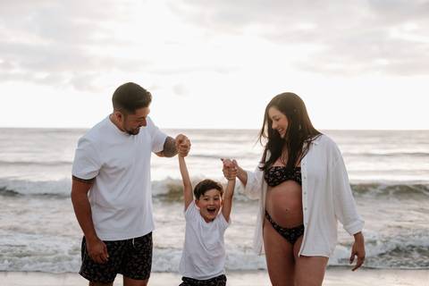 Foto da família caminhando de mãos dadas na beira do mar'