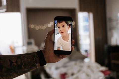 Foto do celular exibindo vídeo do irmão mais velho durante o parto.'