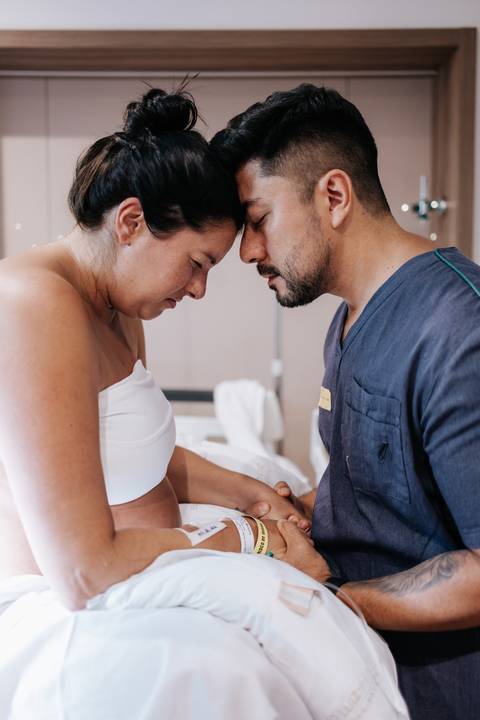 Foto do marido dando apoio durante o trabalho de parto no hospital.'
