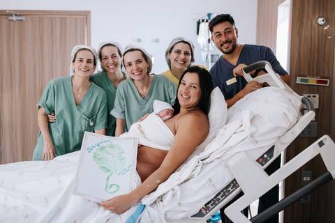 Foto da mãe com a equipe médica exibindo o carimbo da placenta.'