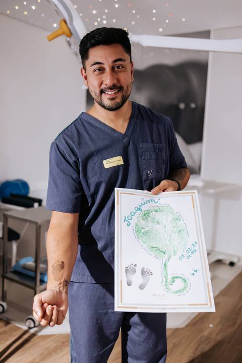 Foto do pai exibindo o quadro com a impressão da placenta e pezinho.'