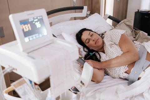 Foto da gestante em repouso no leito com monitor hospitalar ao lado.'