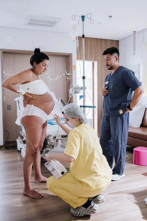 Foto da enfermeira realizando monitoramento fetal na gestante.'