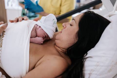 Foto da mãe no contato pele a pele com o bebê. '