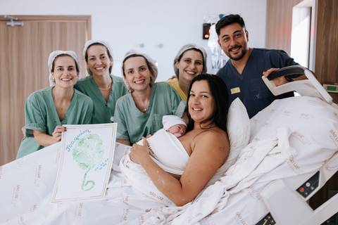 Foto da família reunida com a equipe médica na Maternidade São Luiz Star.'