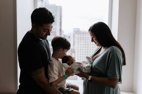 Foto da família em silhueta observando o bebê.'