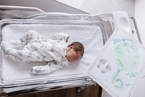 Foto do recém-nascido no berço com quadro da impressão da placenta. '