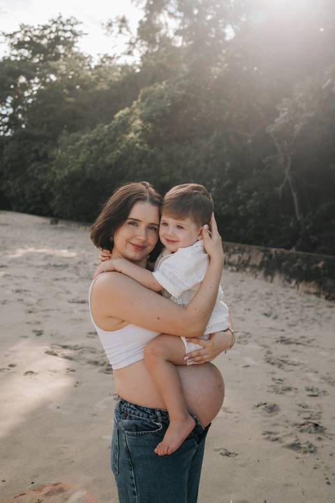 Foto da gestante com o filho no colo em momento de carinho.'