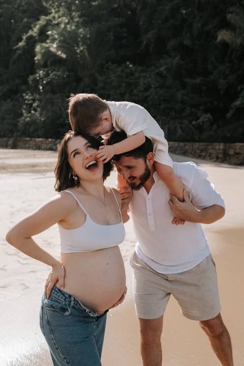 Foto da família sorrindo durante ensaio gestante externo.'