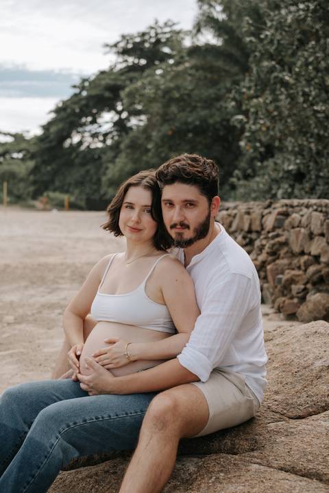 Foto do casal abraçado na praia durante ensaio gestante.'