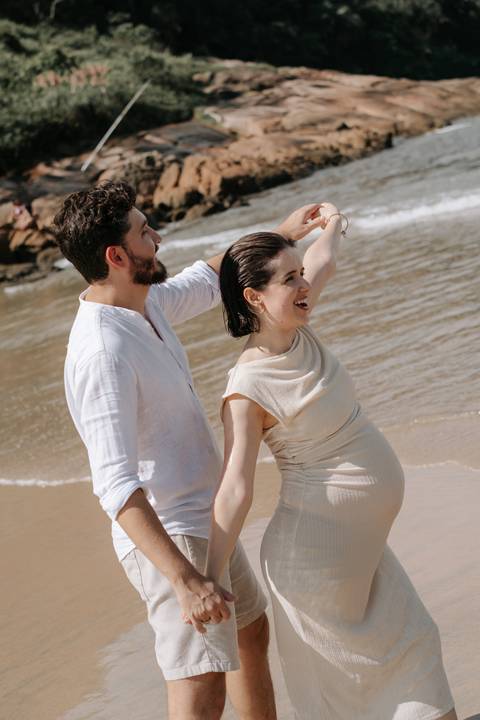 Foto do casal se divertindo na beira do mar durante o ensaio.'