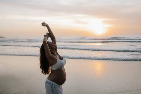 Foto da gestante com o nascer do sol de fundo. '