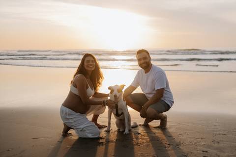 Foto da família reunida com o pet durante o nascer do sol.'