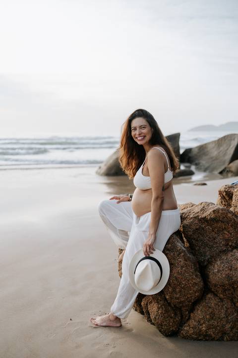Foto da gestante sentada nas rochas em momento de conexão.'