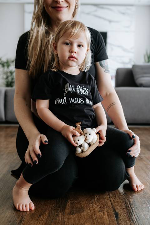 Foto da filha mais velha segurando dois ursinhos de pelúcia (gêmeos).'