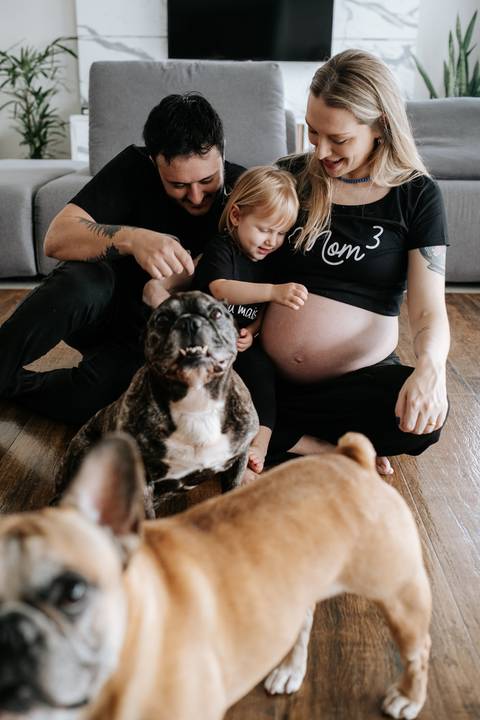 Foto aproximada de um dos cachorros da família com os pais ao fundo.'