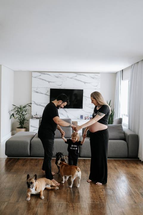 Foto do casal de mãos dadas com a filha pequena entre eles.'