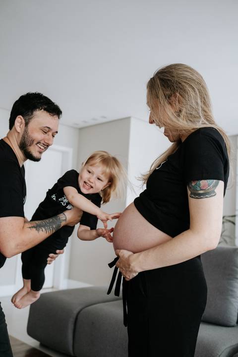 Foto da filha mais velha tocando na barriga de gêmeos da mãe.'