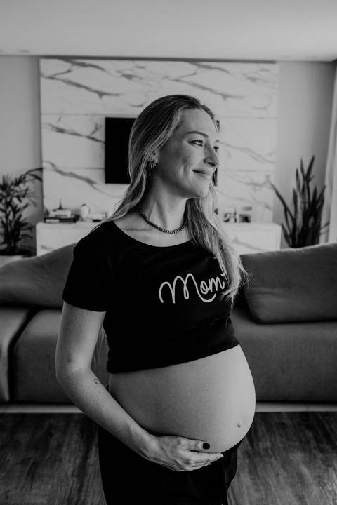 Foto em preto e branco da gestante de perfil no ensaio lifestyle.'