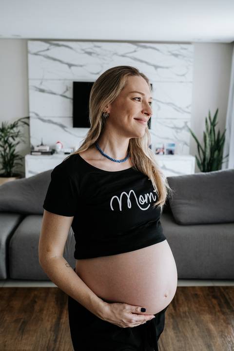 Foto de perfil da gestante sorrindo em ensaio documental.'