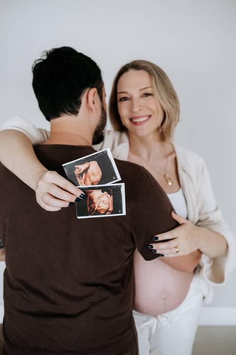 Foto da gestante exibindo os exames de ultrassom dos bebês gêmeos.'