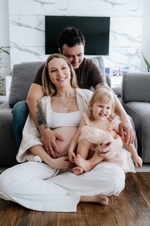 Foto da família reunida no sofá sorrindo para o ensaio documental.'