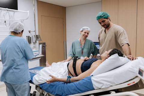Foto da equipe de enfermagem preparando o ambiente para o nascimento.'