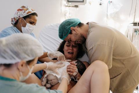 Foto do exato momento do nascimento do bebê em parto hospitalar.'