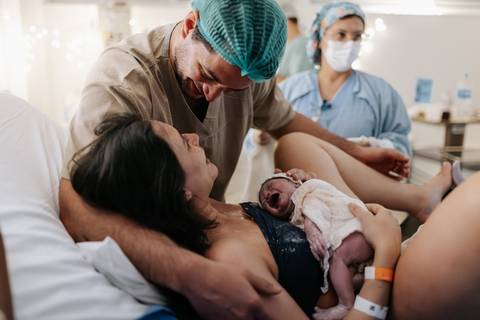 Foto do pai e da mãe emocionado com o encontro com o recém-nascido.'