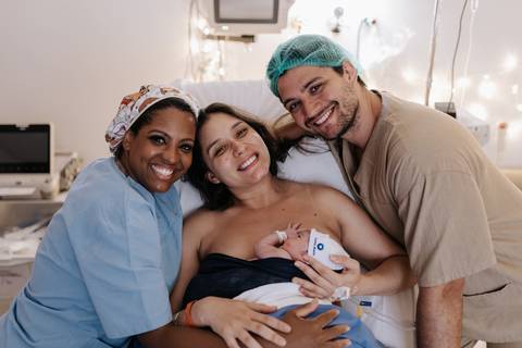Foto da equipe de enfermagem celebrando com os pais o nascimento.'