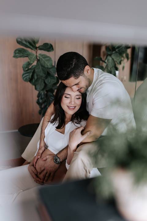 Foto do casal abraçado em momento de carinho durante o ensaio.'