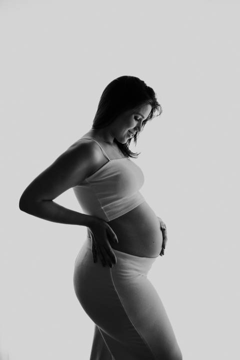 Foto em preto e branco da silhueta da gestante destacando o perfil.'