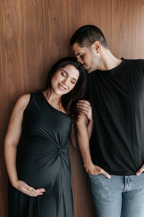 Foto do casal com olhos fechados e rostos próximos em momento de carinho.'