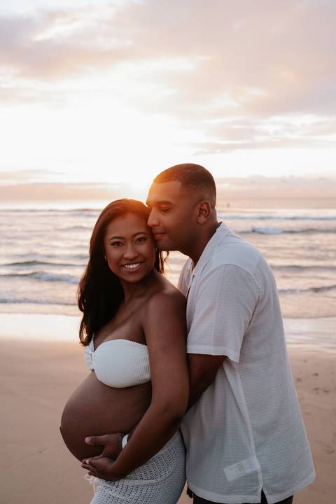 Foto de close do casal abraçado durante o nascer do sol.'