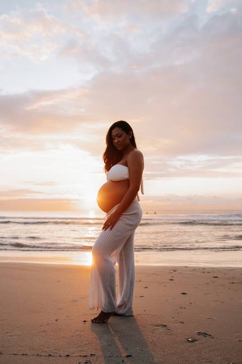 Foto da silhueta da gestante destacando a barriga contra a luz solar.'