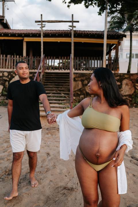 Foto do casal caminhando de mãos dadas próximo à estrutura de madeira.'